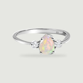 A polished silver ring surrounds a pear-shaped opal with two round clear side stones.