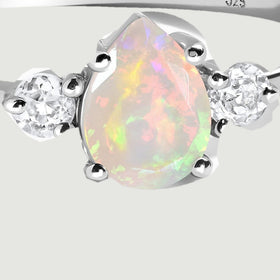 Silver prongs hold the pear-shaped opal beside two round faceted stones in this close view.