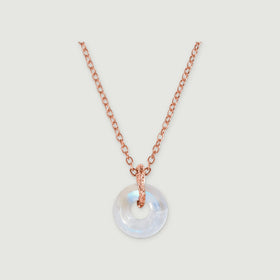 A circular moonstone pendant hangs from a rose gold chain against a light gray background.