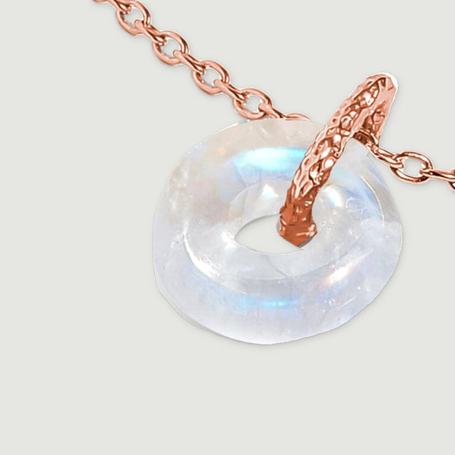 An angled close view shows the moonstone disc and the textured rose gold bail.