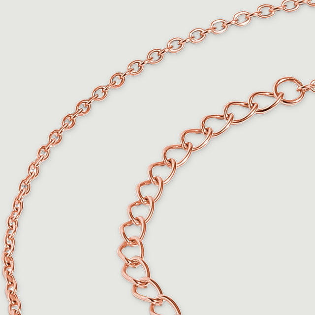 Oval rose gold extender links curve beside the finer links of the necklace chain.