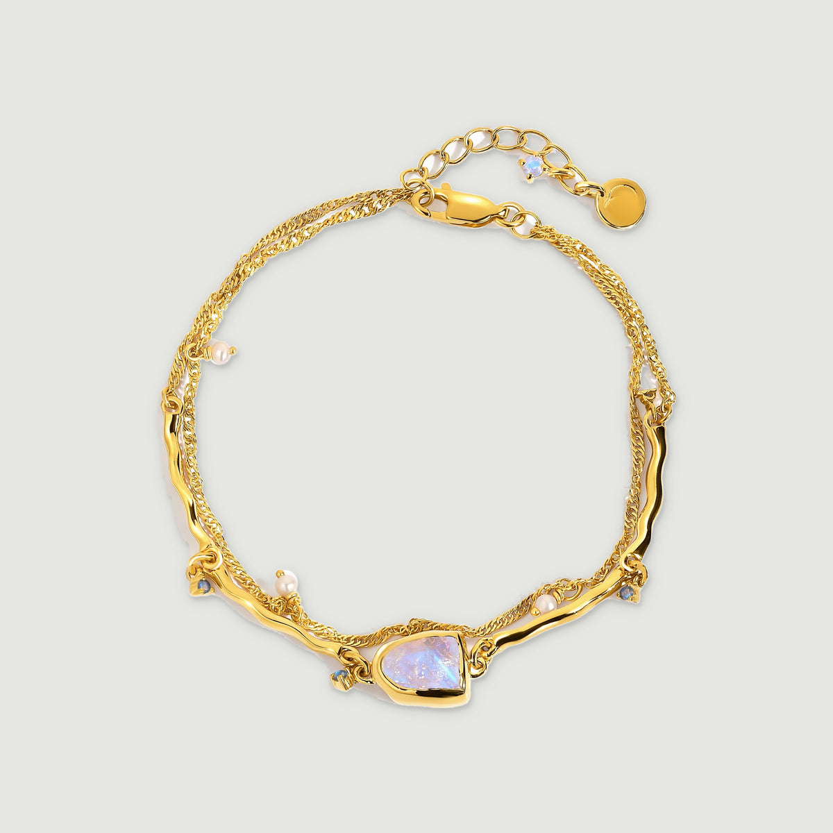 A yellow gold vermeil bracelet shows a pale iridescent moonstone between curved links and dangling pearl accents.
