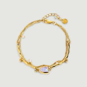 A yellow gold vermeil bracelet shows a pale iridescent moonstone between curved links and dangling pearl accents.