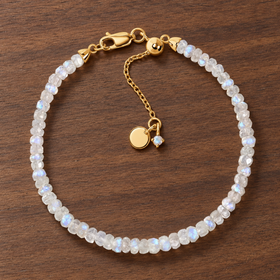 Lunar Tide rainbow moonstone beaded bracelet with 18kt yellow gold vermeil fittings and an extension chain on walnut wood.