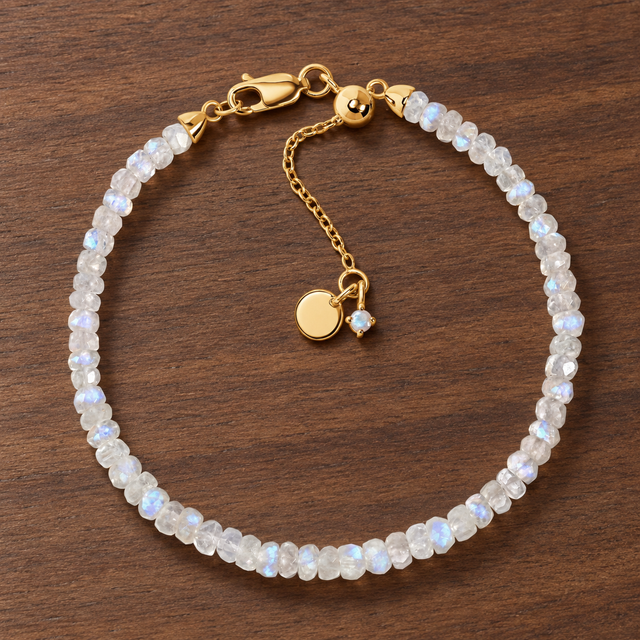 Lunar Tide rainbow moonstone beaded bracelet with 18kt yellow gold vermeil fittings and an extension chain on walnut wood.