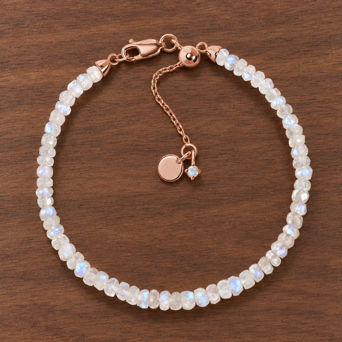 Lunar Tide rainbow moonstone beaded bracelet with 18kt rose gold vermeil fittings and an extension chain on walnut wood.