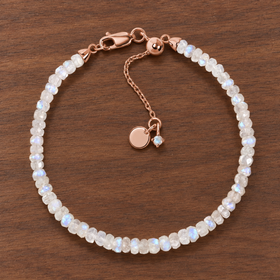 Lunar Tide rainbow moonstone beaded bracelet with 18kt rose gold vermeil fittings and an extension chain on walnut wood.