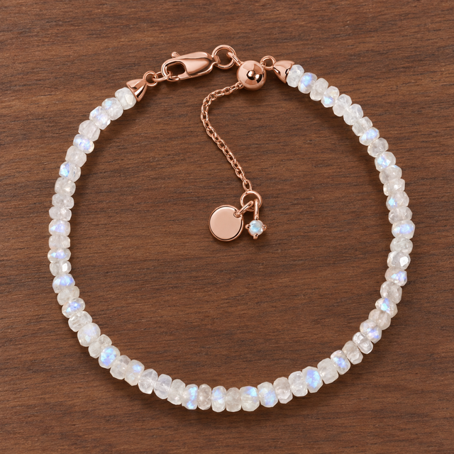 Lunar Tide rainbow moonstone beaded bracelet with 18kt rose gold vermeil fittings and an extension chain on walnut wood.