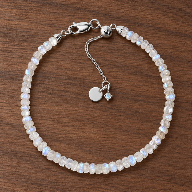 Lunar Tide rainbow moonstone beaded bracelet with sterling-silver clasp and extension chain on walnut wood.