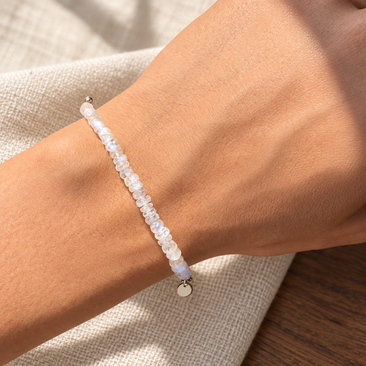 Lunar Tide rainbow moonstone bracelet, sterling silver wrist daylight view. One bracelet; photo props not included.