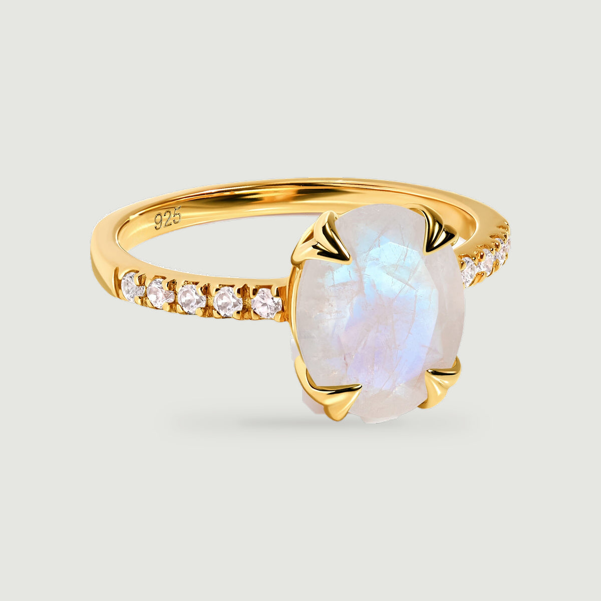 A yellow gold vermeil ring holds a pale oval moonstone in four curved prongs above a slim stone-set band.
