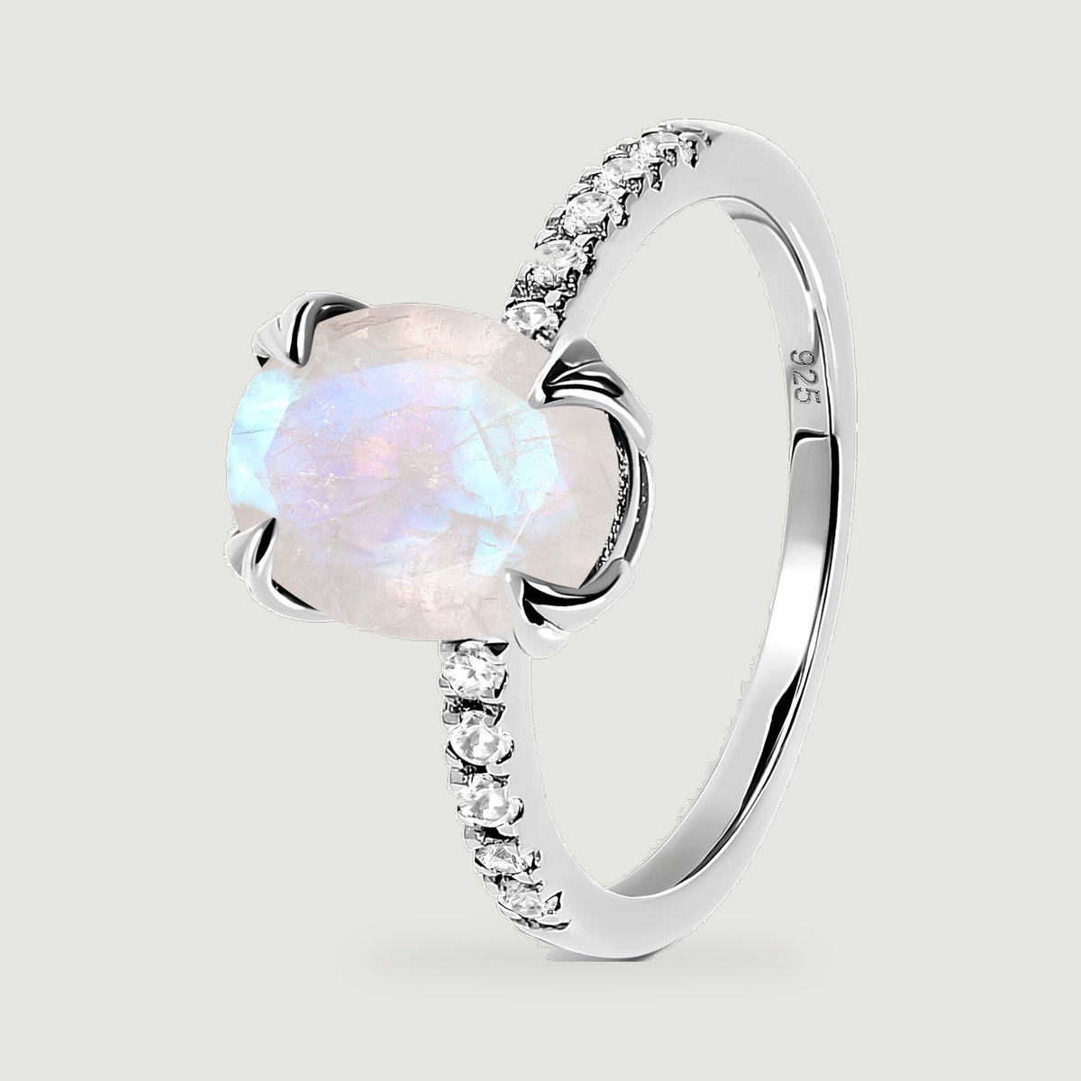 The angled silver ring shows the raised moonstone setting, curved band, and clear stones along its shoulders.