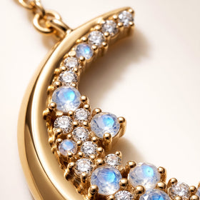 Round blue-flashing stones and clear faceted gems sit in gold prongs along the polished curved pendant.