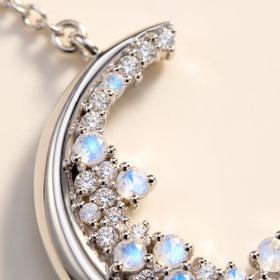 A close view shows blue-white round stones and clear gems beside the reflective silver crescent rim.