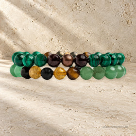 Side view of two malachite and citrine bead bracelets on warm travertine.