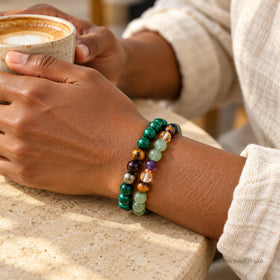 Hands holding a coffee cup while wearing the two malachite and citrine bracelets.
