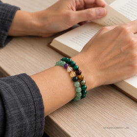 Hands turning a book page while wearing the two malachite and citrine bracelets.