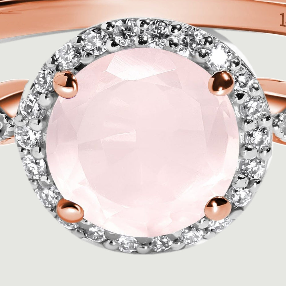 The faceted pale pink center stone is held by four rose gold prongs inside a circular diamond halo.