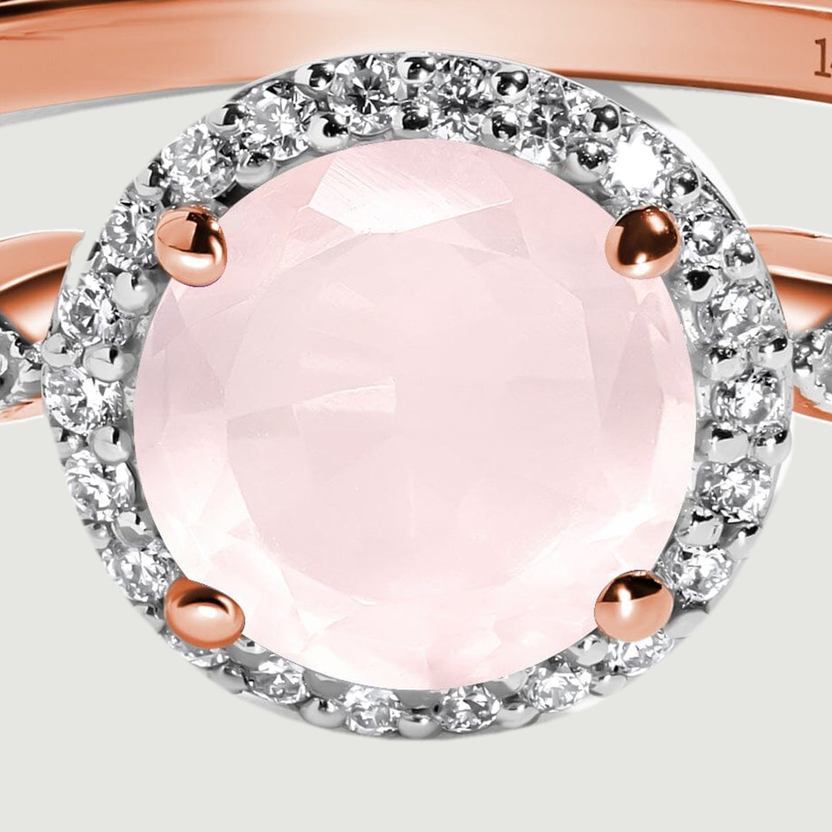 The faceted pale pink center stone is held by four rose gold prongs inside a circular diamond halo.