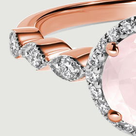 Round diamonds decorate the left shoulder beside polished rose gold curves and the edge of the pink stone.