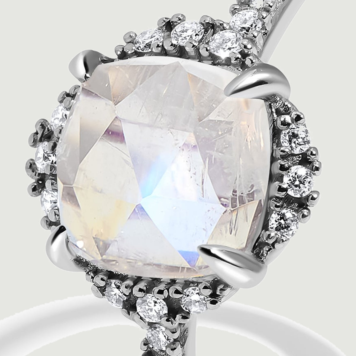 A tight angled view reveals the white gold setting, pale blue moonstone facets, and surrounding diamonds.