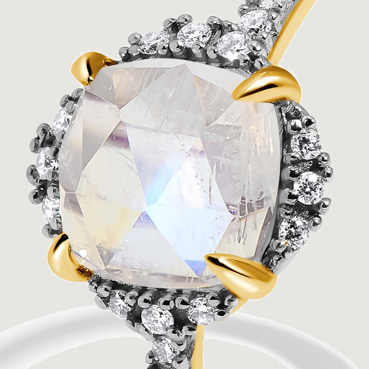 A detailed view highlights yellow gold claws beside the moonstone and the curved diamond halo.