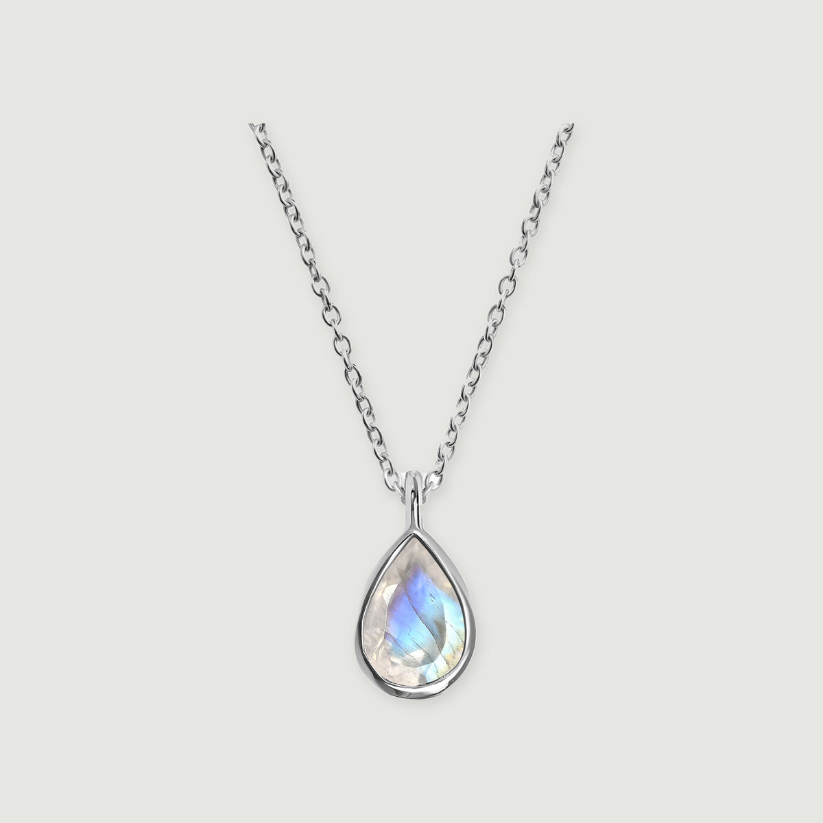 A silver necklace with a pear-shaped moonstone pendant and an oval-link chain is centered on a light gray background.