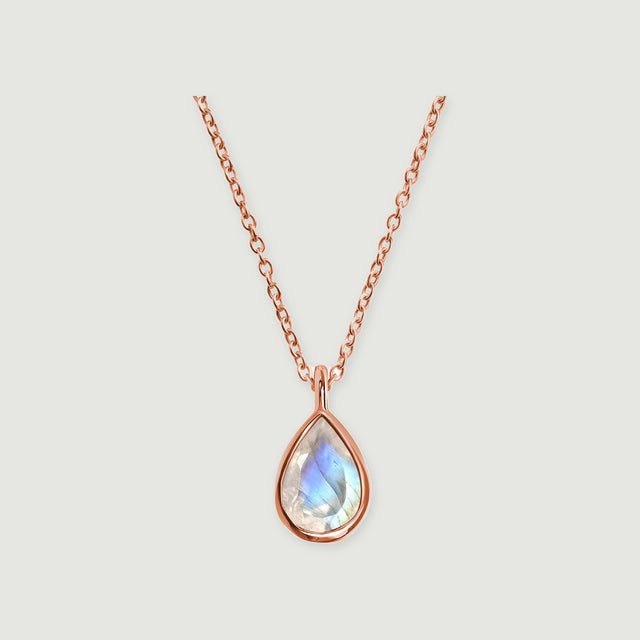 A rose gold necklace with a teardrop moonstone and a slim connecting bail rests against a light gray background.