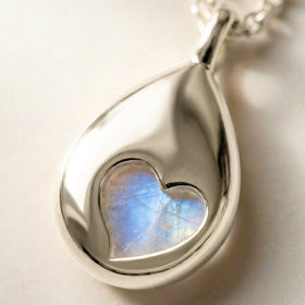 A close view of the silver pendant reveals a heart-shaped opening with blue moonstone visible through the polished reverse.