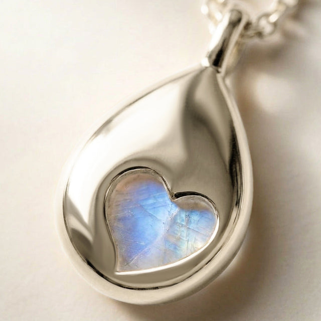 A close view of the silver pendant reveals a heart-shaped opening with blue moonstone visible through the polished reverse.