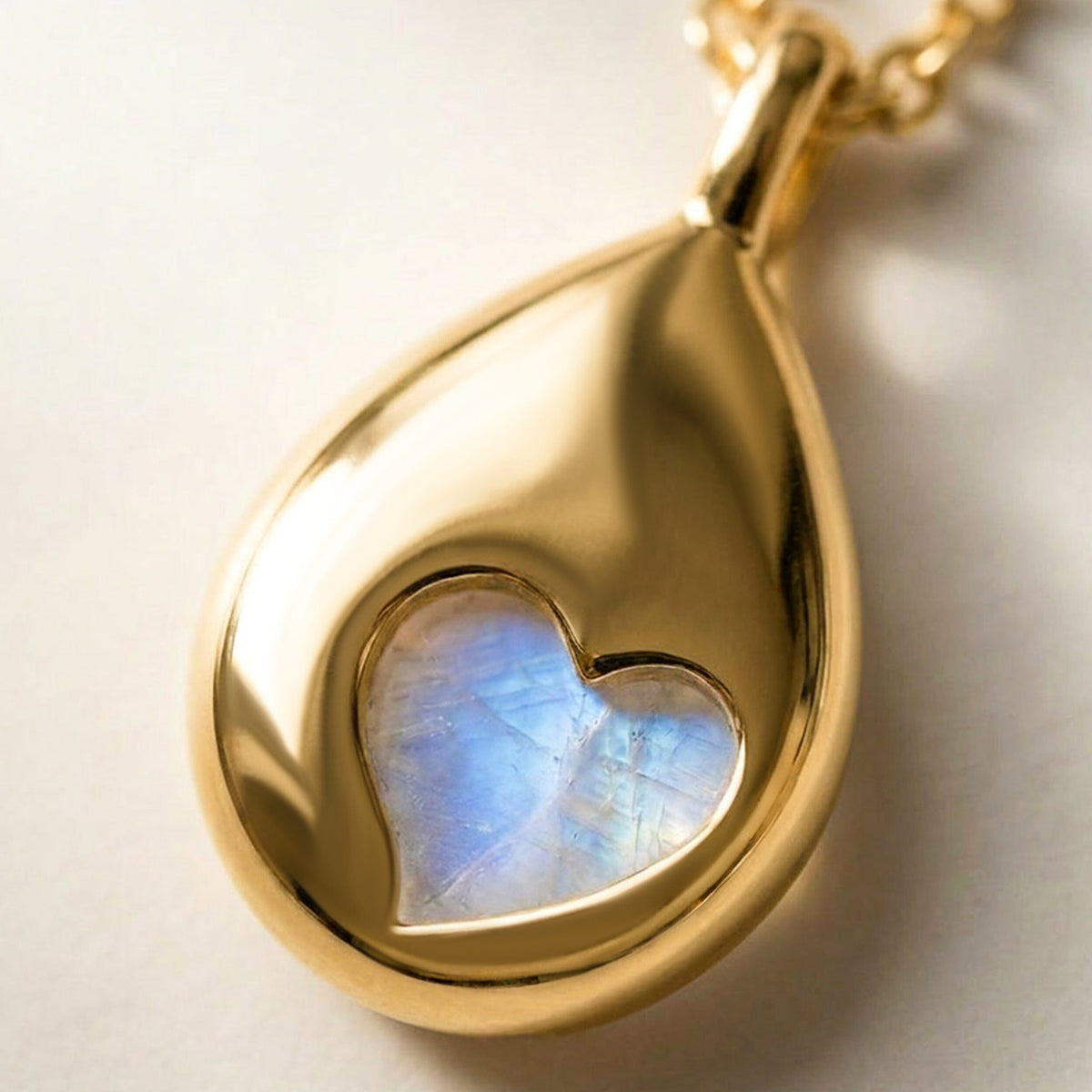 The yellow gold pendant is shown from the back with a heart-shaped opening and reflective curved edges on a clean stone surface.