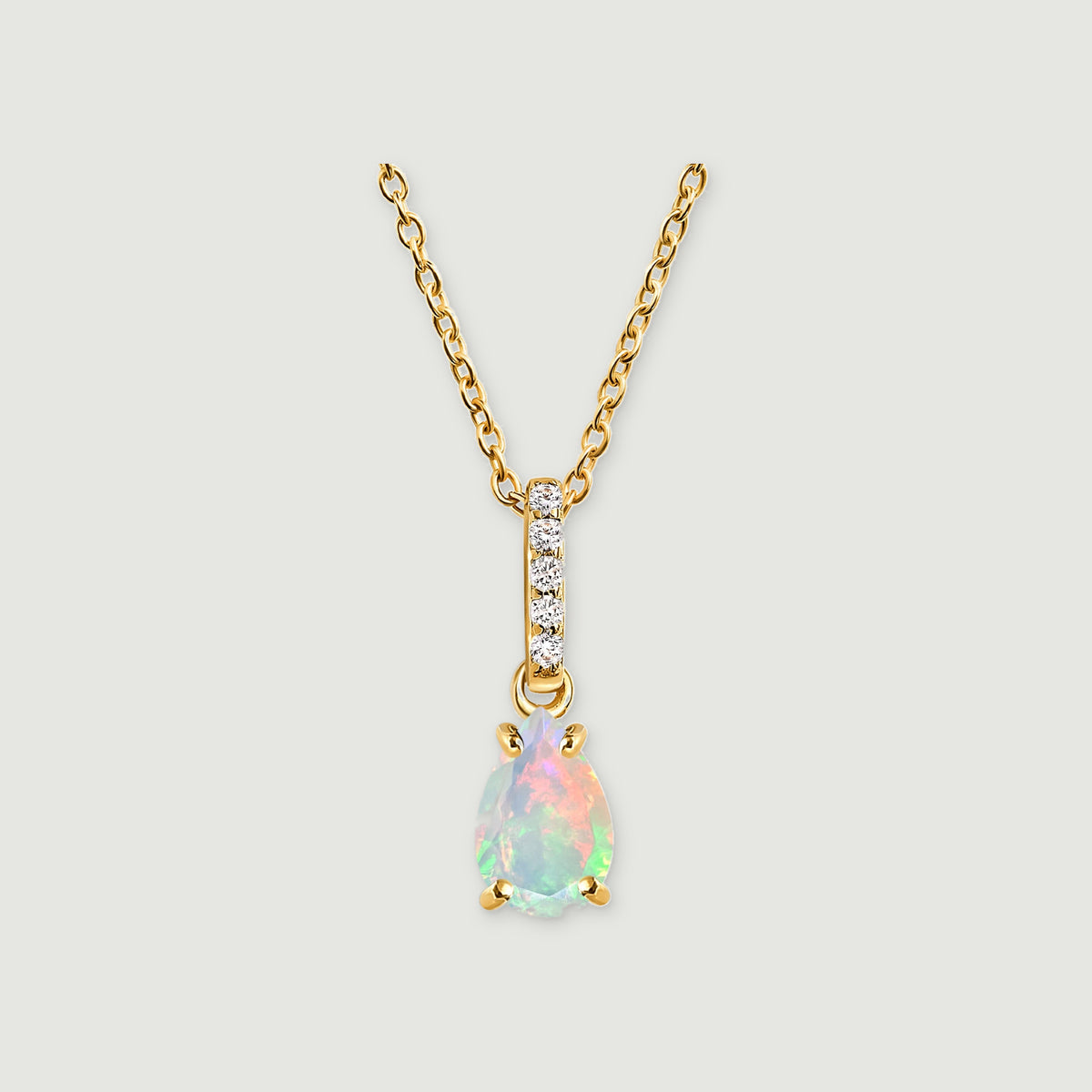 A yellow gold necklace has a pear-shaped opal pendant and five clear stones along the bail on a light grey background.