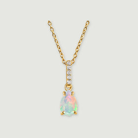 A yellow gold necklace has a pear-shaped opal pendant and five clear stones along the bail on a light grey background.