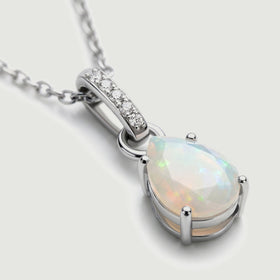 The silver pendant is shown at an angle with pale opal facets and a row of clear stones above it.