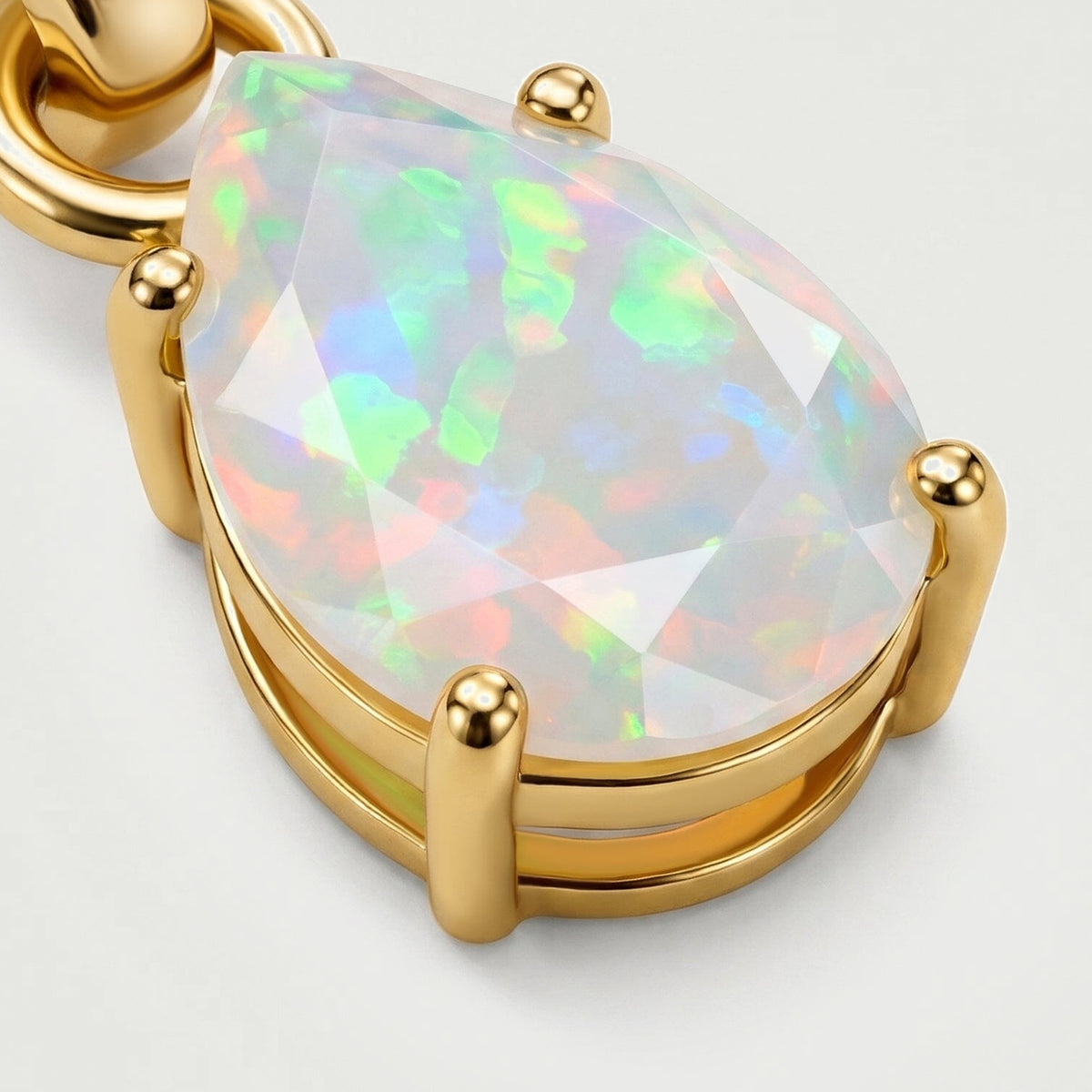 An angled close-up of the yellow gold setting shows four rounded prongs around the pear-shaped opal.
