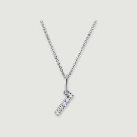 A silver chain holds a stone-set letter I pendant against a light gray background.
