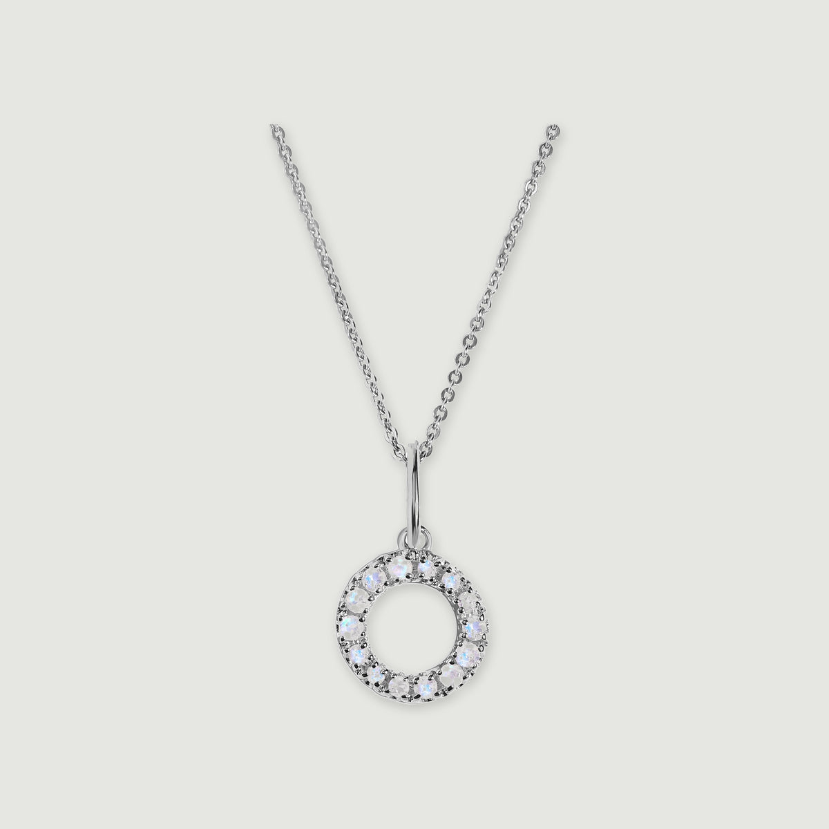 A silver chain holds a stone-set letter O pendant against a light gray background.