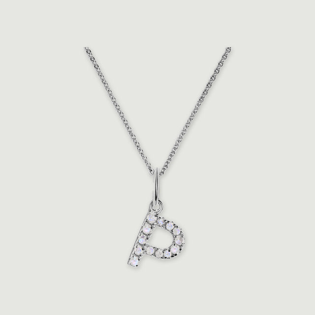 A silver chain holds a stone-set letter P pendant against a light gray background.