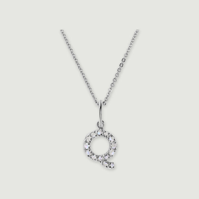 A silver chain holds a stone-set letter Q pendant against a light gray background.