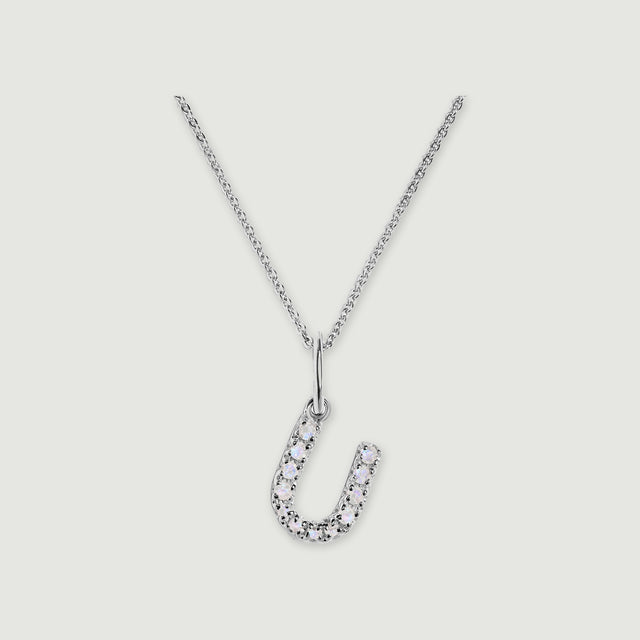 A silver chain holds a stone-set letter U pendant against a light gray background.