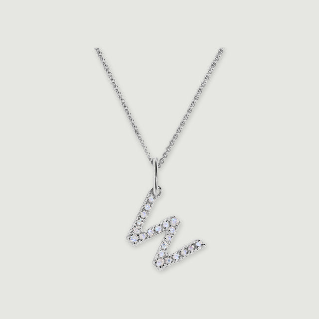 A silver chain holds a stone-set letter W pendant against a light gray background.