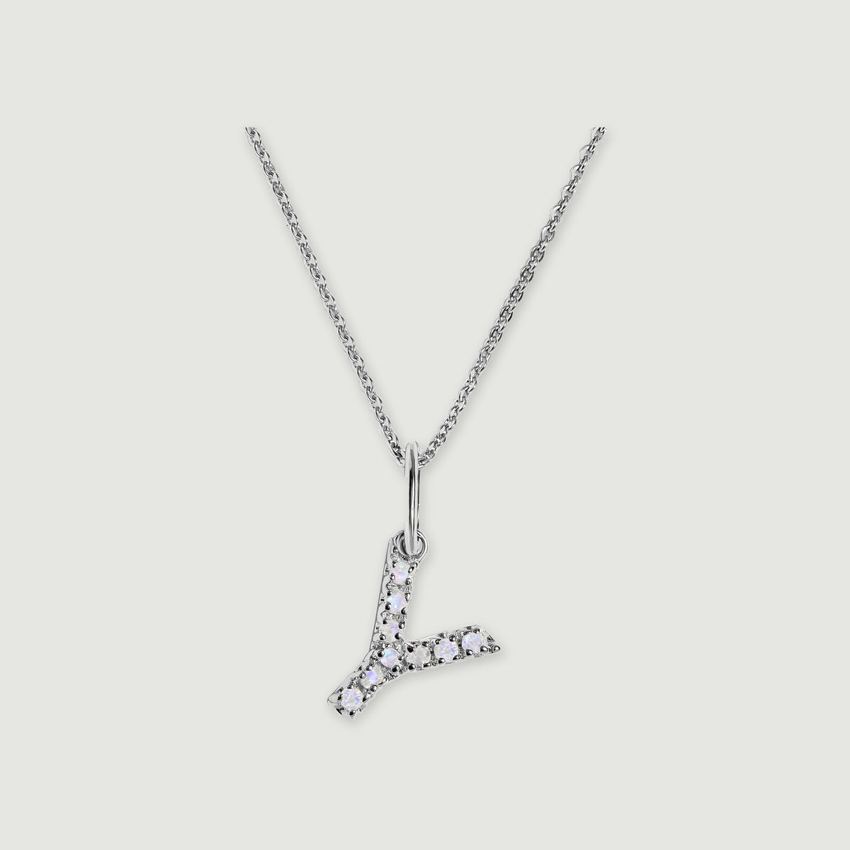 A silver chain holds a stone-set letter Y pendant against a light gray background.