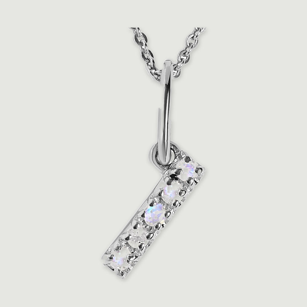 A close view reveals the pale stones and polished silver prongs on the letter I pendant.