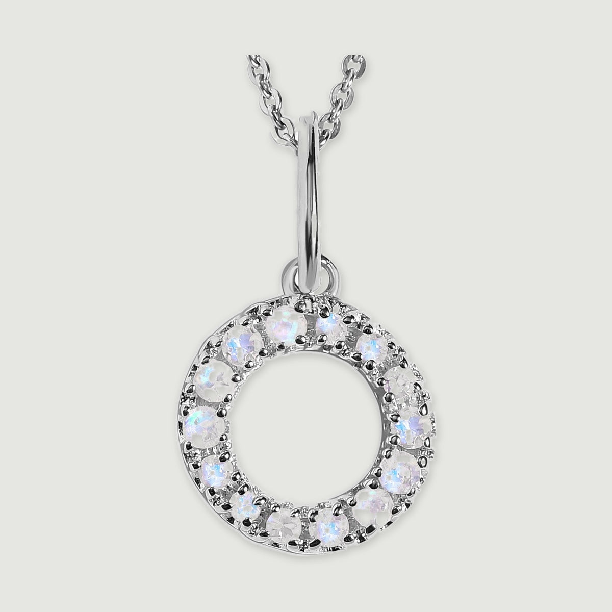 A close view reveals the pale stones and polished silver prongs on the letter O pendant.