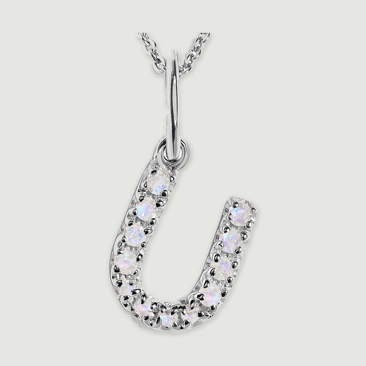 A close view reveals the pale stones and polished silver prongs on the letter U pendant.