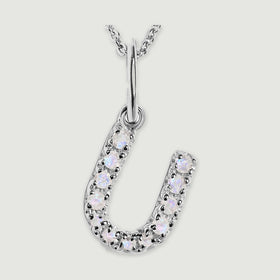 A close view reveals the pale stones and polished silver prongs on the letter U pendant.