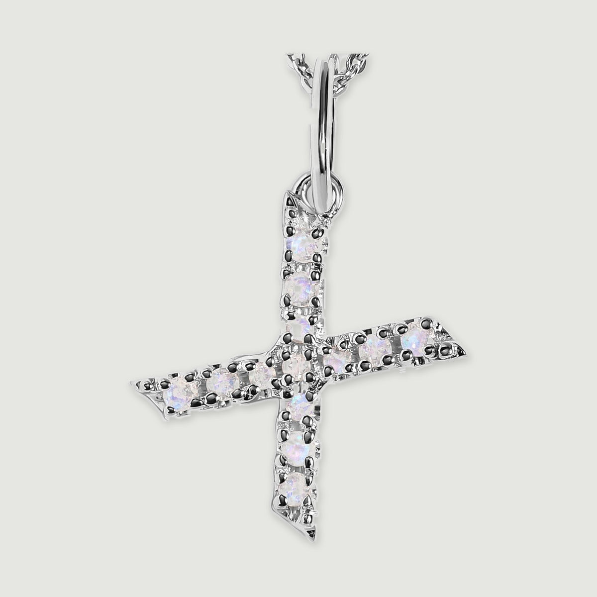 A close view reveals the pale stones and polished silver prongs on the letter X pendant.