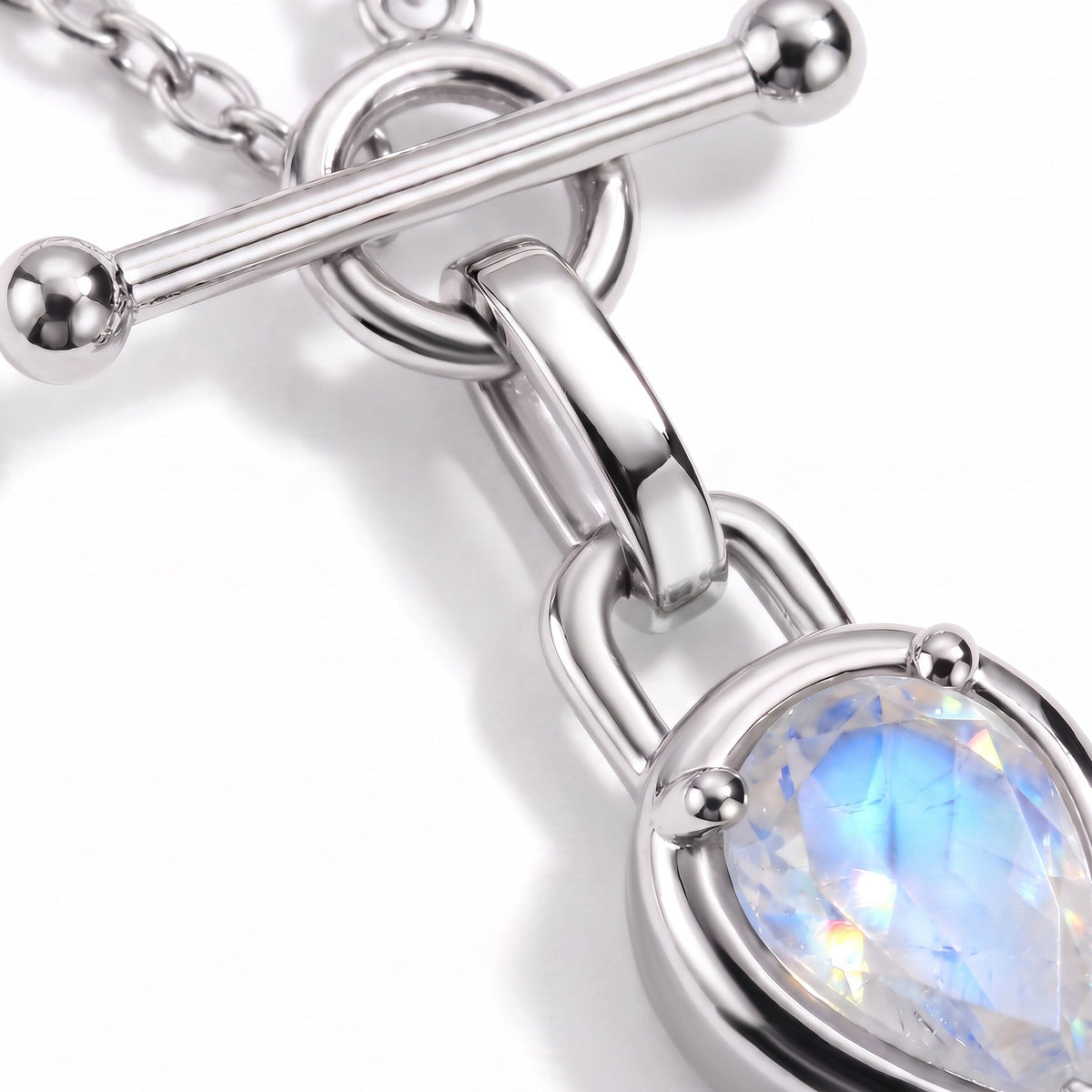 Macro product detail showing a horizontal toggle bar, linked chain, and faceted blue-white round stone.