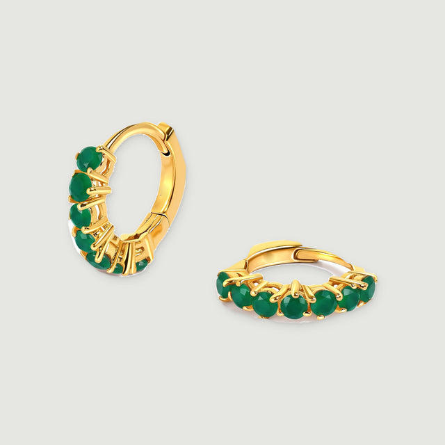 Two yellow gold plated hoop earrings with round green stones rest on a light gray background.