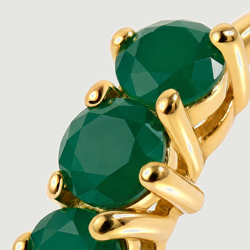 A close view shows faceted green onyx held by polished yellow gold prongs.
